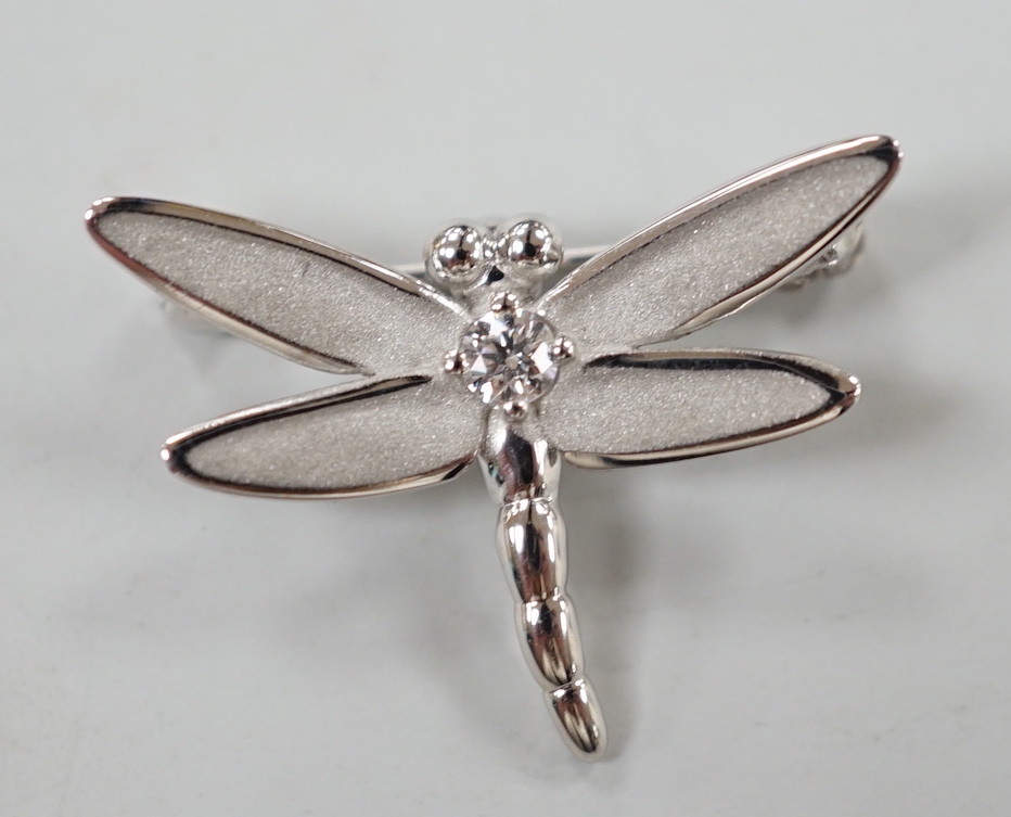 A modern Tiffany & Co 18ct white gold and single stone diamond set dragonfly brooch, width 23mm, 2.5 grams.